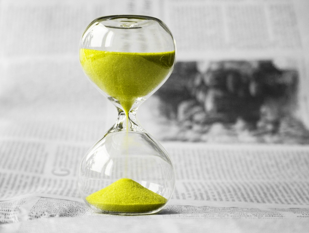 A yellow hourglass on a newspaper